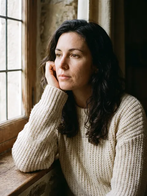 Portrait d’une femme près d’une fenêtre dans une maison en pierre bretonne